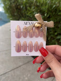 Card with nail art designs held by a hand with red nails outdoors.
