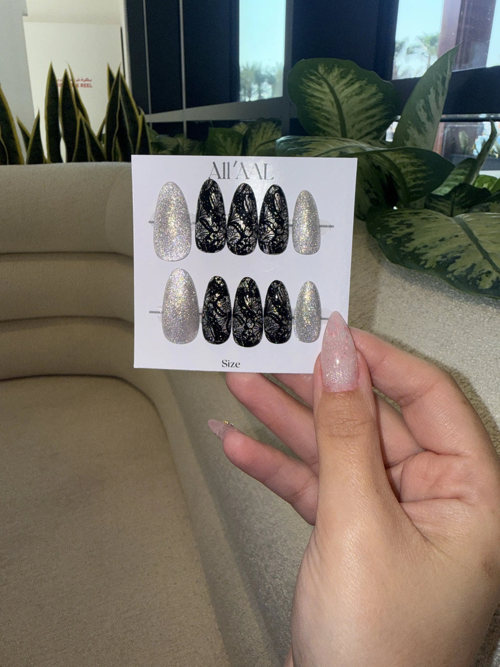 Card with nail art designs held by a hand in front of a blurred indoor background