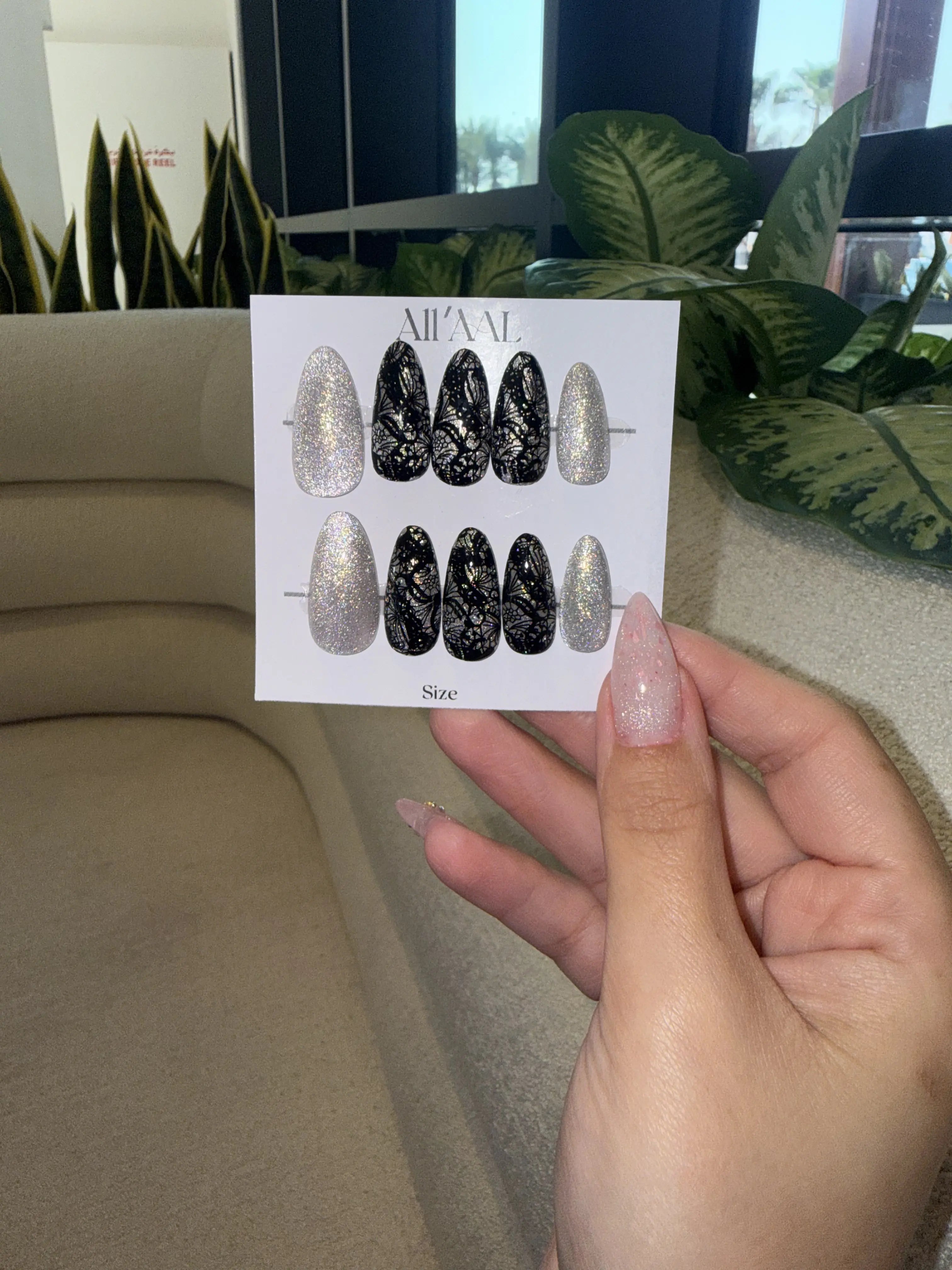Card with nail art designs held by a hand in front of a blurred indoor background