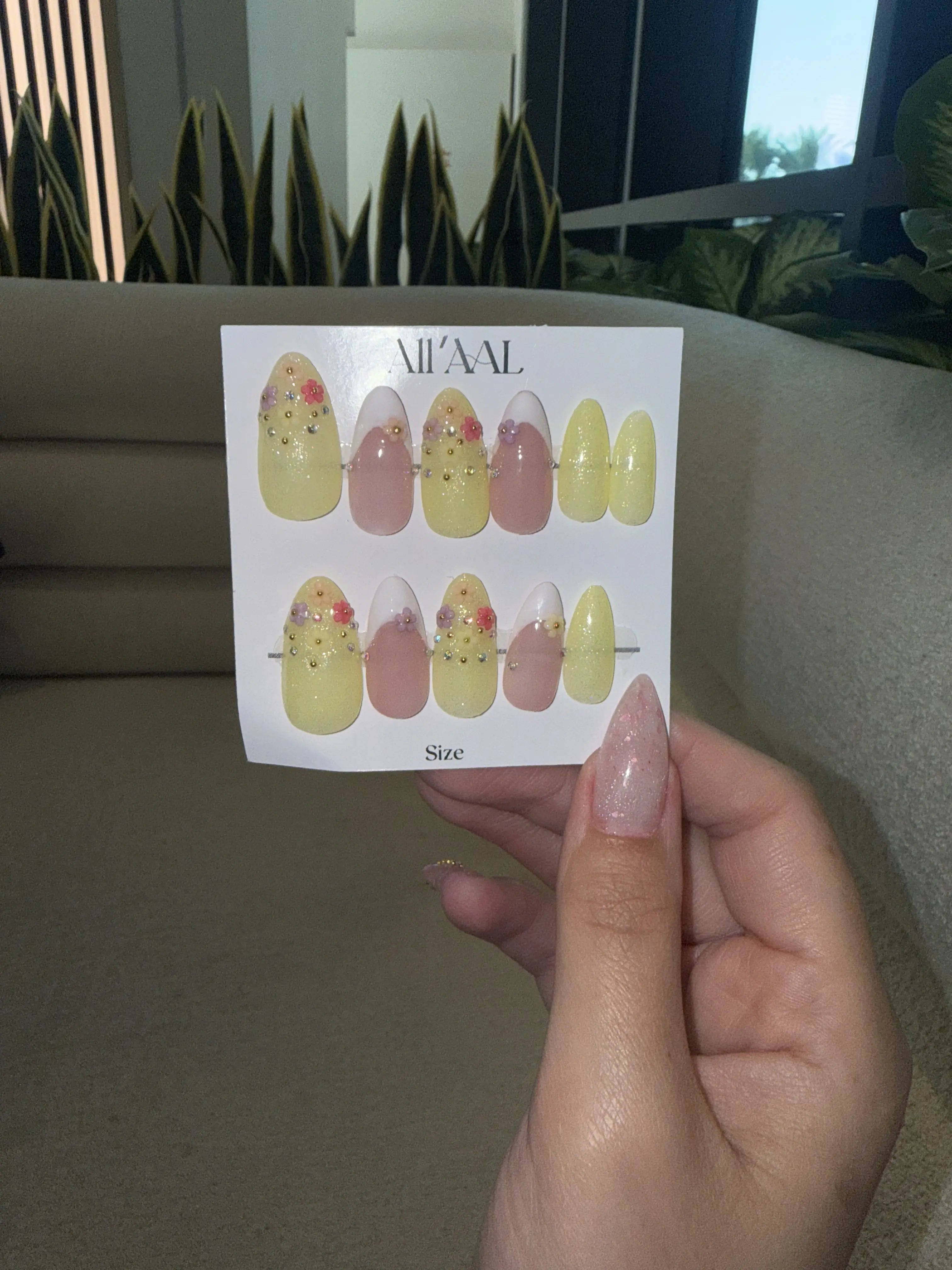 Hand holding a card with nail art designs against a neutral background