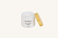 White jar of moisturizing cream with a wooden applicator on a white background